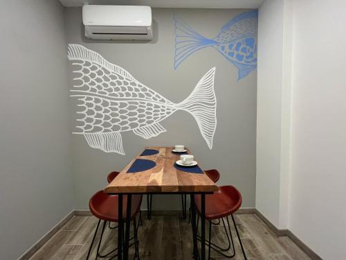 a table in a room with a wall with a painting of fish at Leevin Guesthouse in Faro