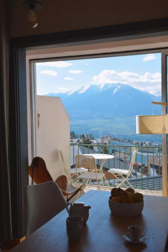 une table de salle à manger avec vue sur un balcon dans l'établissement Vue de carte postale en hypercentre de Font-Romeu, à Font-Romeu-Odeillo-Via