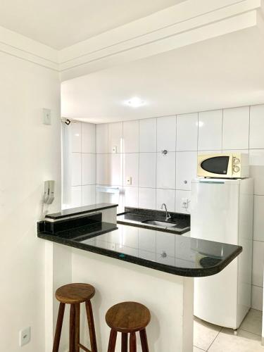 a white kitchen with a counter and two stools at Flats Service BuenoAmerica in Goiânia