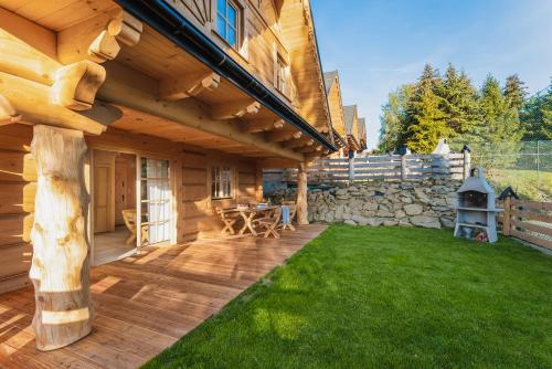a log cabin patio with a stone wall and green grass at Pienińska Przystań in Kluszkowce