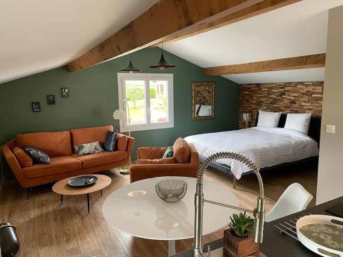 a bedroom with a bed and a couch and a table at Ôverger, studio cosy, aux portes de Toulouse in Belberaud