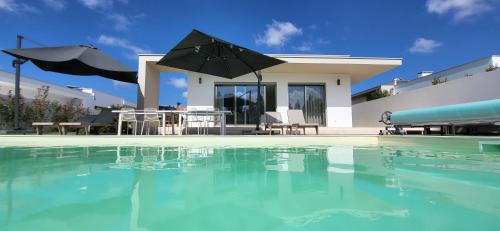 a villa with a swimming pool in front of a house at Villa Silver Coast in Nadadouro