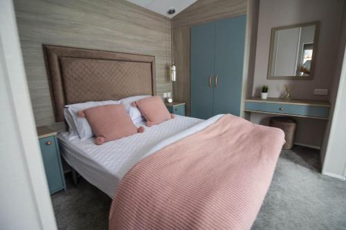ein Schlafzimmer mit einem Bett mit rosa Kissen darauf in der Unterkunft Stunning Caravan With Wifi At Azure Seas Nearby The Beautiful Beach Ref 32057az in Lowestoft