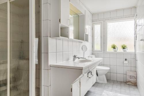 a white bathroom with a sink and a toilet at Spacious villa in Upplands Vasby in Upplands-Väsby