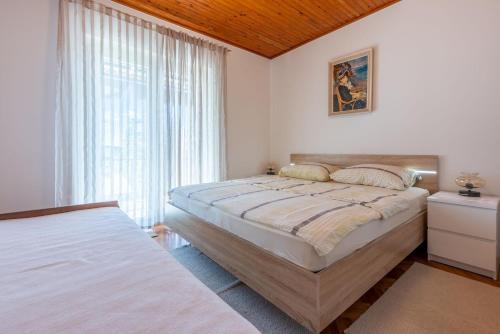 a bedroom with two beds and a large window at Apartments Hinic in Selce
