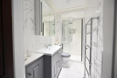 La salle de bains blanche est pourvue d'un lavabo et d'une douche. dans l'établissement The Old Manse, à Ayr