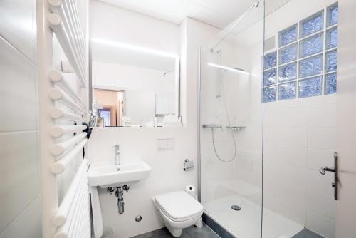 uma casa de banho branca com um chuveiro, um WC e um lavatório. em Hotel Montana em Genebra