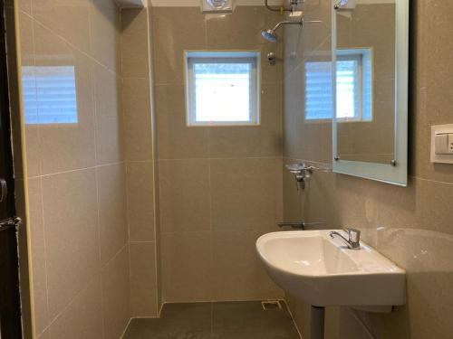 a bathroom with a sink and a shower with a mirror at HOTEL BK SAN in Sengippatti