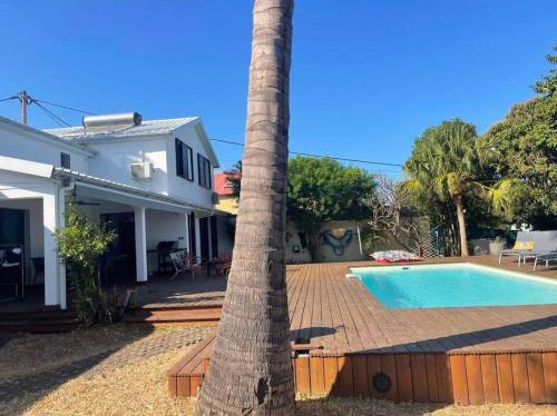 a palm tree next to a house with a swimming pool at Villa Jujubes in Le Bois de Nèfles
