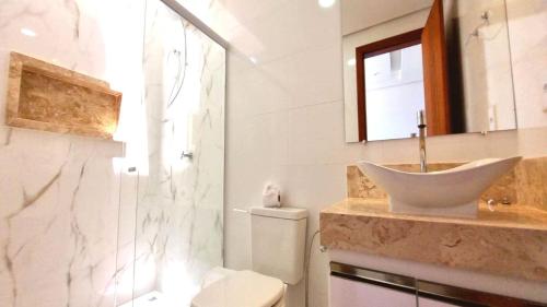uma casa de banho com um lavatório, um chuveiro e um WC. em Apartamento a 400 metros da praia de taparapuan em Porto Seguro