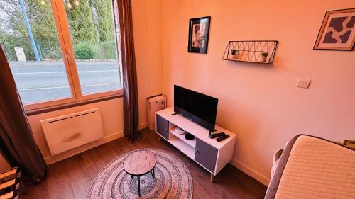 sala de estar con TV en un soporte y ventana en LA VILLA DEKO - Studio avec parking proche Université et Hôpital, en Beuvry