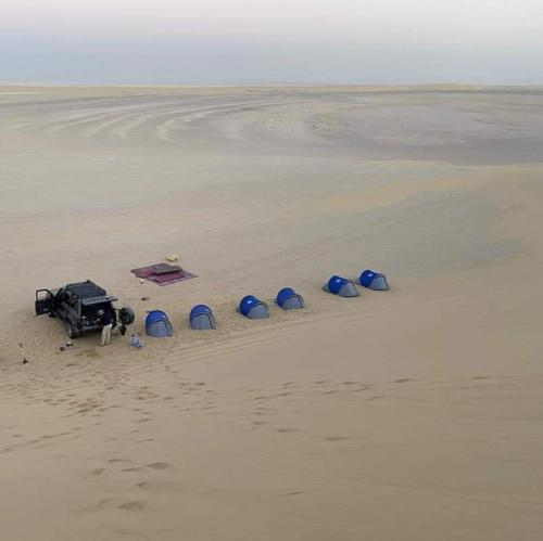 a group of tents and a truck on a beach at Escape Camp in Bawati