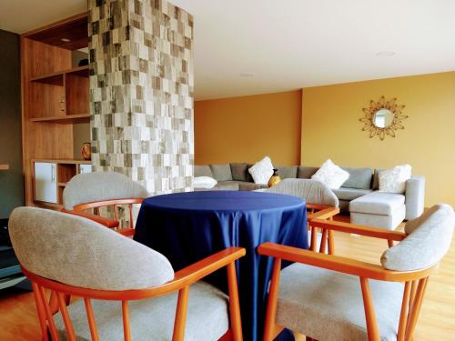 Hotel Morasurco في باستو: غرفة معيشة مع طاولة وكراسي زرقاء