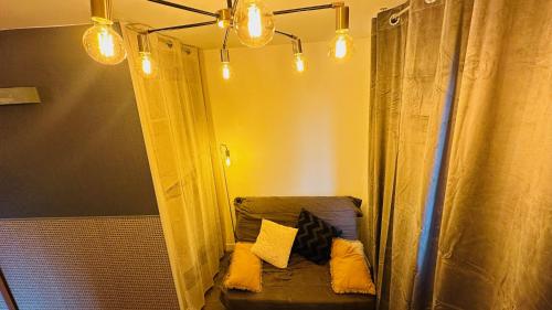 a room with a couch with pillows and lights at LA VILLA DEKO - Studio avec parking proche Université et Hôpital in Beuvry