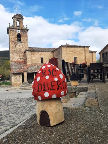 a red and white mushroom statue in front of a building at Hostal Rio Duero in Molinos de Duero