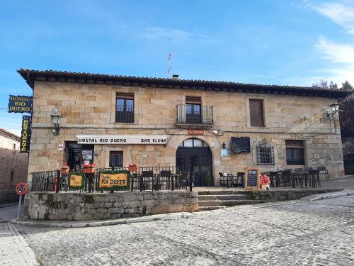 een gebouw met tafels en stoelen ervoor bij Hostal Rio Duero in Molinos de Duero