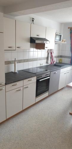 a kitchen with white cabinets and a stove top oven at Haus Bilgeri in Nesselwängle