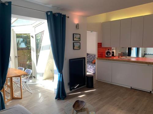 Il comprend une cuisine avec des rideaux bleus et une table. dans l'établissement MONT VENTOUX, maisonnette provençale atypique, à Bédoin