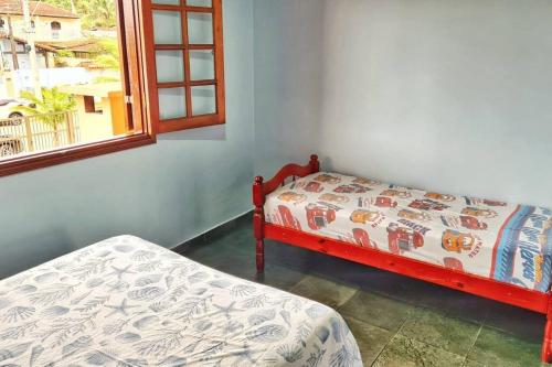 卡拉瓜塔圖巴的住宿－100mts DA PRAIA com Churrasqueira, Piscina e Wi-Fi，一间卧室设有两张床和窗户。