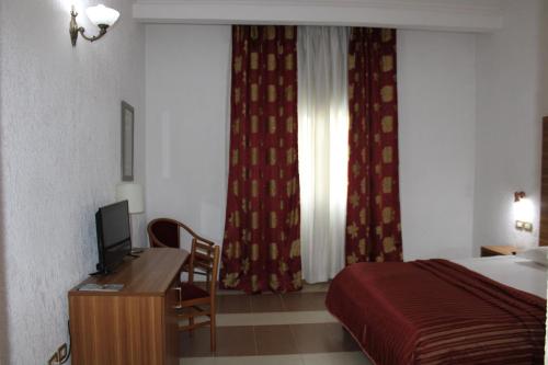 a hotel room with a bed and a desk with a television at Hotel Franco Yaounde in Yaoundé