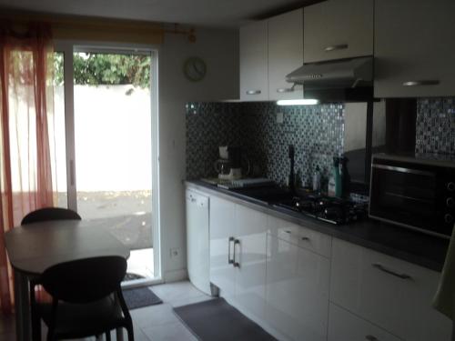 une cuisine avec des armoires blanches, une table et une fenêtre dans l'établissement mireille, à Villedoux