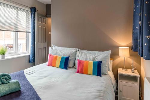 1 dormitorio con cama blanca y almohadas coloridas en The Exchange Apartments with Permit Parking, en Tewkesbury