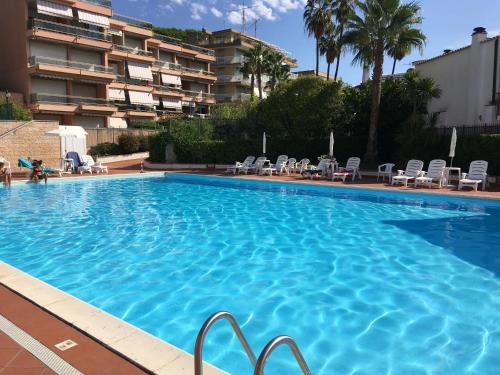 une grande piscine avec des chaises et un bâtiment dans l'établissement Apartment in Residence BaiaSole, à Sanremo