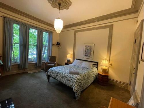 Northwest Portland Hostel في بورتلاند: غرفة نوم بسرير وكرسي ونوافذ