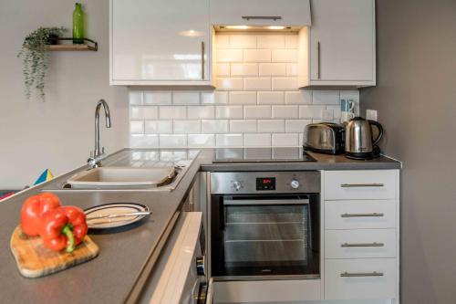 a kitchen with a counter with a sink and a stove at The Exchange Apartments with Permit Parking in Tewkesbury
