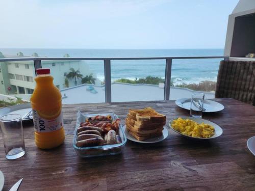 a table with a plate of food and a bottle of orange juice at Breathtaking 3 Bedroom unit with amazing sea views in Ramsgate