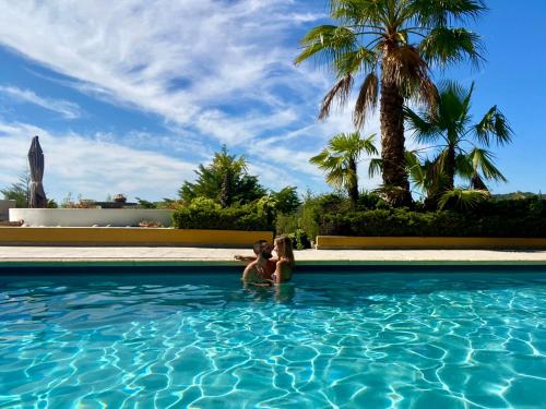 two women in a swimming pool with palm trees at Chambre Romantique "La Pompadour" - La Vénus de Lisbonne in Calhandriz