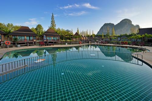 a swimming pool with a resort with mountains in the background at Poonsiri Resort Aonang-SHA Extra Plus in Ao Nang Beach