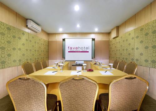 a conference room with a table and chairs and a screen at favehotel Kelapa Gading in Jakarta