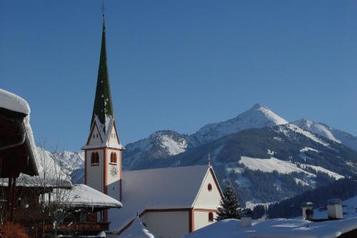 a church with a snow covered mountain in the background at Gästehaus Wöll in Alpbach