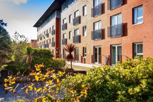a large brick building with windows and plants in front of it at Fabulous Modern Luxury Apartment Sleeps 6- Parking in Belfast