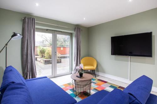 a living room with a blue couch and a tv at Fabulous Modern Luxury Apartment Sleeps 6- Parking in Belfast