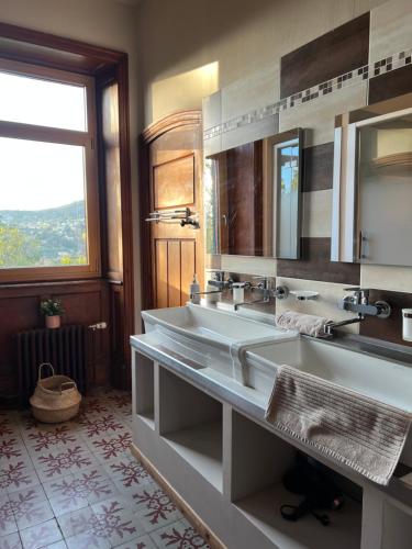 un bagno con due lavandini e un grande specchio di O'Cottage jardin ad Annonay