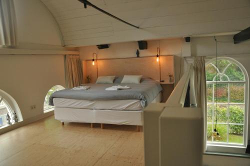 ein Schlafzimmer mit einem Bett in einem Zimmer mit Fenstern in der Unterkunft Himelsk in Koudum