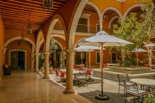 an outdoor patio with tables and chairs and an umbrella at HC HACIENDA CATRINA HOTEL BOUTIQUE in Silao