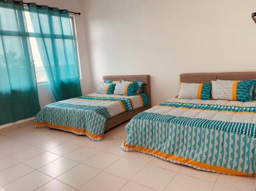 two beds sitting next to each other in a room at Brand New Cozy home Desaru Pengerang near Sebana Cove Resort in Pengerang