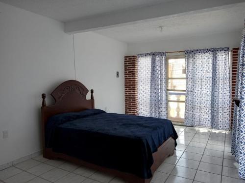 een slaapkamer met een bed en een raam met gordijnen bij Casa amplia en Cuernavaca in Cuernavaca