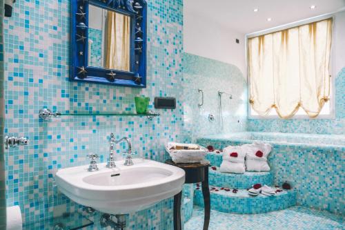 uma casa de banho em azulejos azuis com um lavatório e uma banheira em Eveline Portosole Hotel em Sanremo