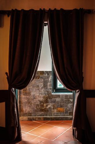 a window with black curtains in front of a stone wall at Y.O Inn in Kon Tum
