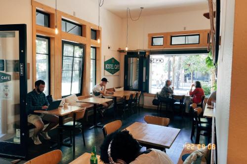 a restaurant with tables and chairs and a man sitting at a table at HI - Portland Northwest Hostel in Portland