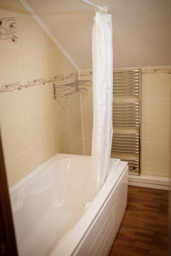 a white bath tub with a shower curtain in a bathroom at Vila Muntenia Hotel in Chişinău