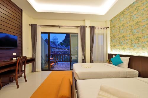 a bedroom with two beds and a desk and a balcony at Poonsiri Resort Aonang-SHA Extra Plus in Ao Nang Beach