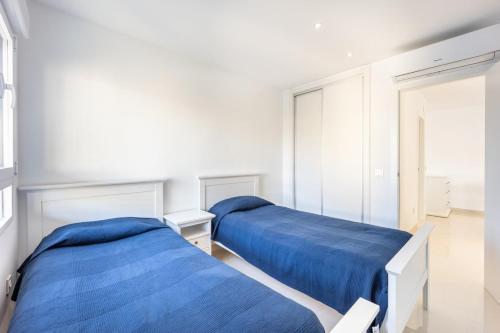 zwei Betten in einem weißen Zimmer mit blauen Laken in der Unterkunft Premium apartment in Benidorm
