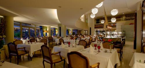 uma sala de jantar com mesas e cadeiras brancas em Royal Savoy - Ocean Resort - Savoy Signature no Funchal