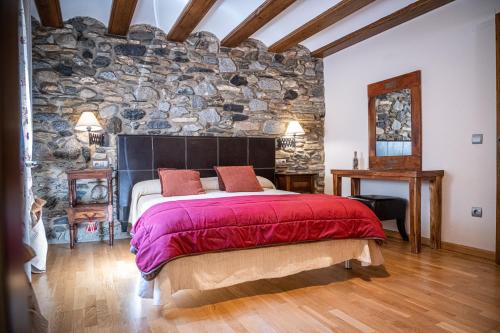 una camera da letto con un muro in pietra e un grande letto di Apartamentos Casa Pichuana a Benasque
