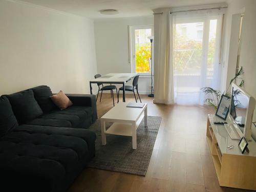 sala de estar con sofá negro y mesa en Exklusiv möblierte Wohnung in besten Lage, en Stuttgart